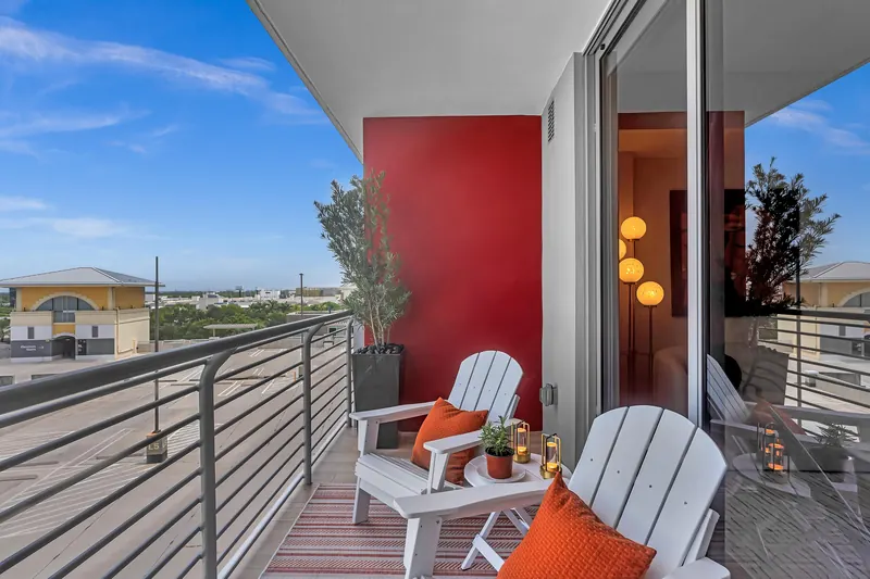 Balcony with white lounge chairs, orange cushions, lanterns and a red accent wall