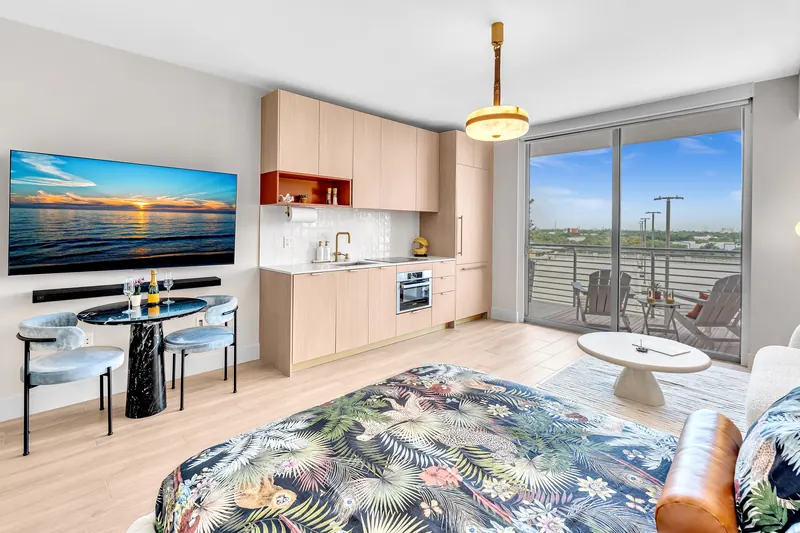 The whole studio: bed, dining table, kitchen and sliding doors to the balcony